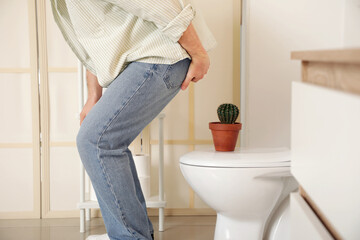 Man sitting down on cactus in restroom. Hemorrhoid concept