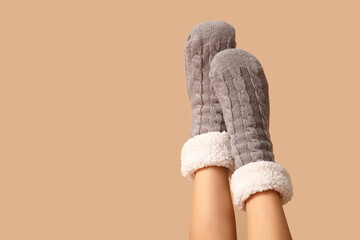 Legs of young woman in warm grey socks on brown background