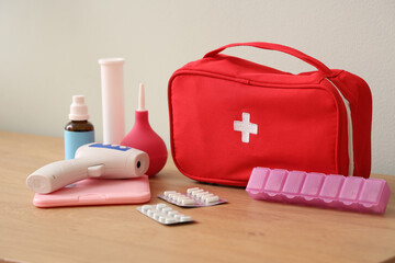 First aid kit with medical supplies on table near light wall