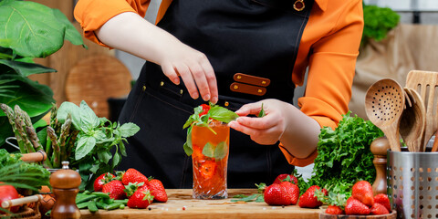Deliciously preparing a refreshing vegan drink with fresh strawberries and herbs in a vibrant...