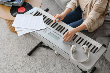 Woman playing synthesizer at home