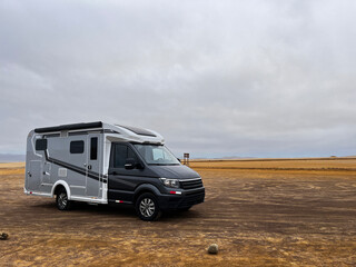 Modern RV motorhome while standing desert landscape in National Park Reserve Paracas in Pisco Province, Peru. Caravan exploring red sand beaches, and wildlife of national park. 