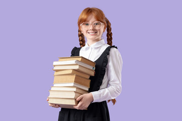 Cute redhead schoolgirl with stack of books on lilac background