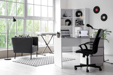 Interior of podcaster's studio with workplace, shelf unit and armchair