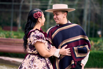 Portrait of a smiling young couple, dressed as Chilean huasos, posing romantically to dance cueca,...
