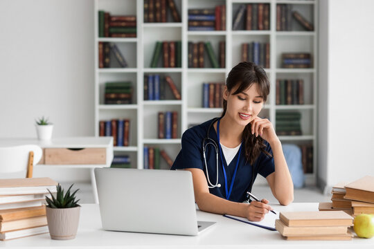 Female medical intern studying at table in library