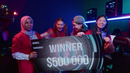 Medium full shot of four excited diverse female cybersport teammates standing in computer club, receiving cash prize check on winning online tournament, jumping, cheering, in photo camera flash lights