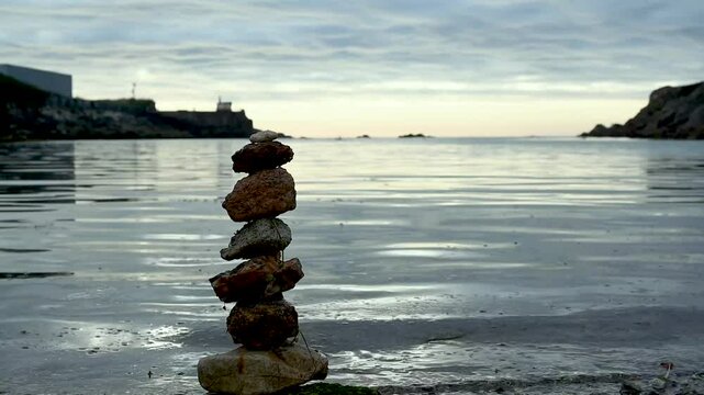 piedras apiladas una encima de otras frente al mar en un atardecer
