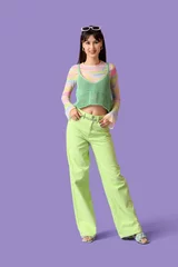 Fotobehang Stylish young woman in green pants on lilac background © Pixel-Shot