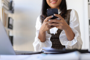 Happy businesswoman using mobile phone and sending messages online on smartphone.