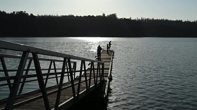 tres personas pescando en un muelle en un dia soleado