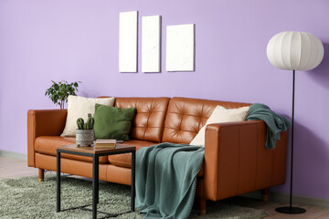 Comfortable sofa, floor lamp and table near violet wall in interior of living room, closeup
