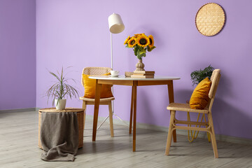 Table, chairs and floor lamp near violet wall in interior of room