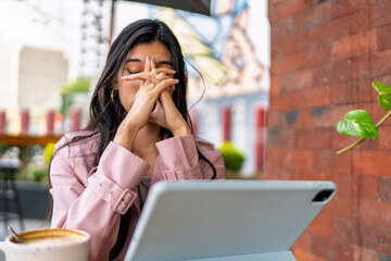 Stressed freelancer covering face with hands at coffee shop