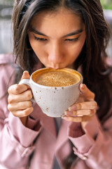 Young freelancer woman drinking cappuccino in coffee shop