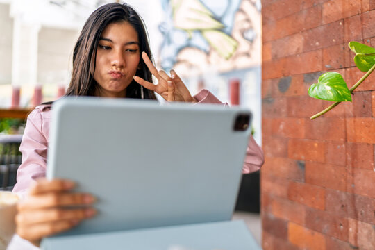 Freelancer making peace sign while taking selfie in coffee shop
