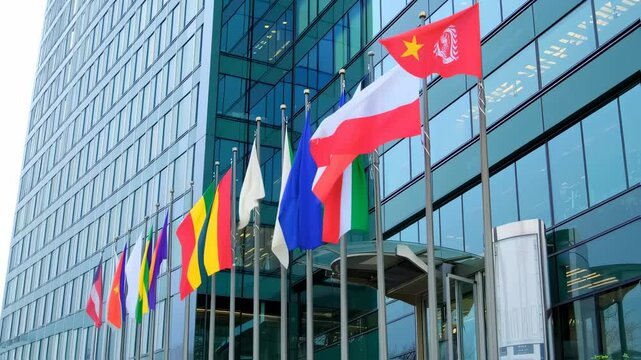 Flags of Diverse Nations Flapping Gracefully in Front of a Modern Glass Building