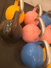 Colorful kettlebells arranged neatly on a gym floor. The vibrant pink, yellow, blue, and black...