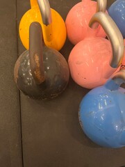 Colorful kettlebells arranged neatly on a gym floor. The vibrant pink, yellow, blue, and black...