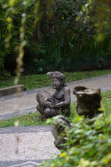 Balinese statue made of stone carved in the shape of a Balinese man sitting holding a traditional...