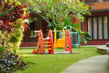 Plastic slide and swing toys for children in the middle of the park in the morning