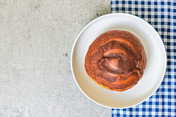 Top view of coffee bun on plate with napkin. grey or gray cement as background. High angle, above, close up. blue, white. copy space, free, empty, negative. bread home made. Mexican Coffee Bun.
