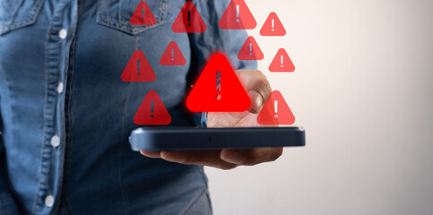 Woman's hand holding a smartphone and various warning signs