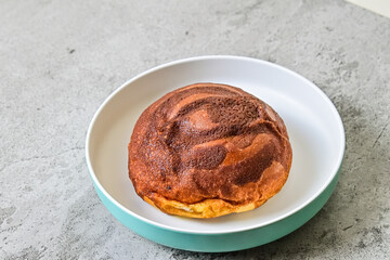 Close up view of coffee bun on plate with grey or gray cement as background. bread home made. copy space, empty, free, negative, text.