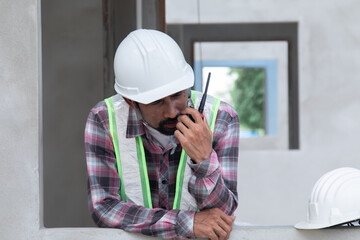 Asian or Indian architect foreman male working control communicate with builder using walkie-talkie...
