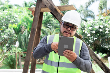 Portrait young Asian engineering architect foreman male wearing safety vest and helmet using...
