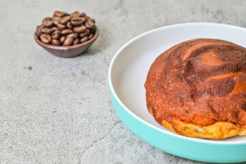 Extreme close up view of coffee bun on plate isolated on grey or gray cement as background. bread home made. half. roasted coffee beans. copy space, empty, free, negative, text.