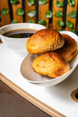 vertical photo of traditional handmade whole wheat mogolla bread next to a cup of coffee in a healthy vegetarian restaurant in Colombia