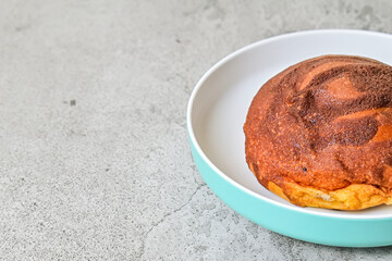 Extreme close up view of coffee bun on plate isolated on grey or gray cement as background. bread home made. copy space, empty, free, negative, text. half.