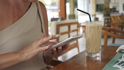 Woman relaxes during summer break holding phone and enjoying cold drink Digital connection blends...