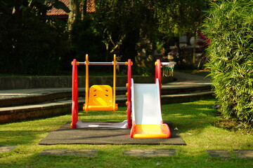 Children's plastic swing and slide toys in the park and exposed to the morning sun