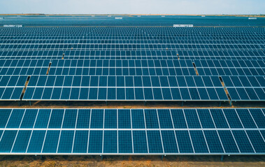 Large solar energy farm with numerous solar panels capturing sunlight in a wide open space during...