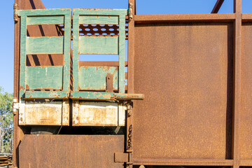Green gate on trailer of old road-train and rusty side panels.