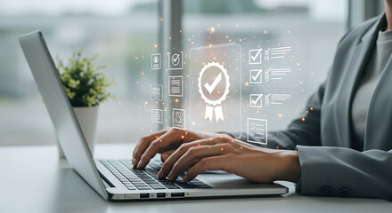 Person typing on laptop with quality assurance icons floating above the keyboard on a white desk