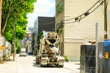 Cement mixer truck pulls a tight alley to access a construction site downtown in a big city shot...