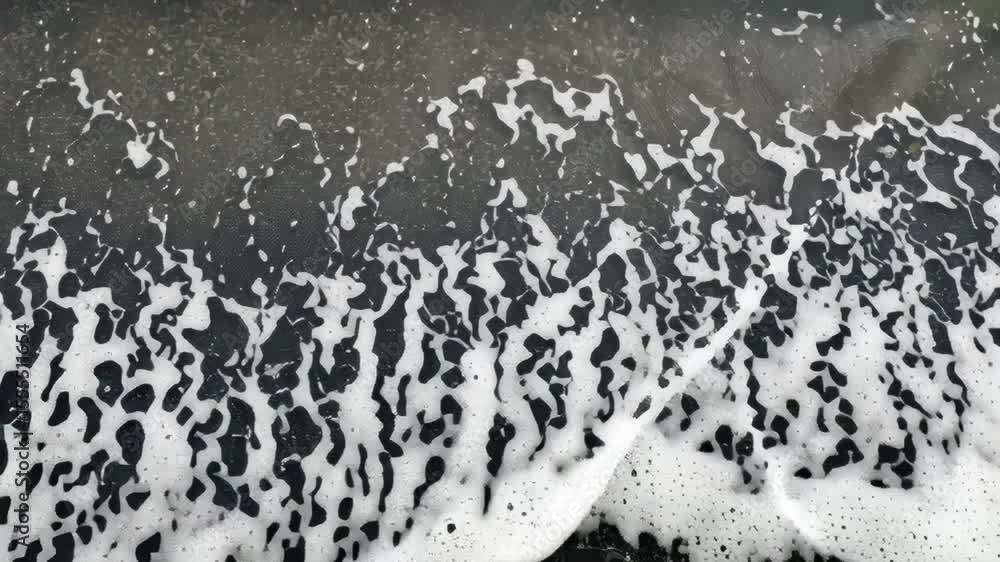 Poster a wave crashing on a black ocean floor. the water is white and frothy, creating a dynamic and powerf