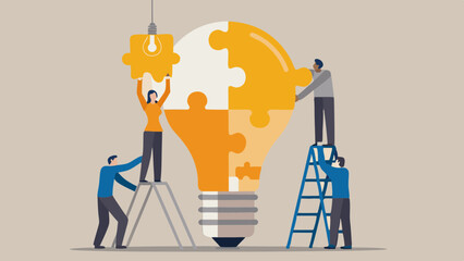 Teamwork assembling a giant light bulb puzzle representing a new idea or innovation