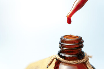 Red liquid dripping from a pipette into an amber bottle, creating a visually appealing contrast...