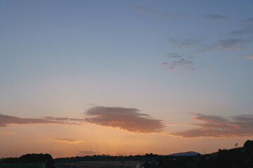 Beautiful sunset with orange and blue colors illuminating the clouds over rolling hills
