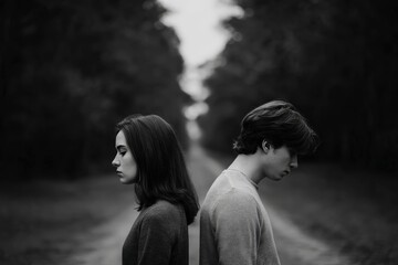 Expressive Black and White Portrait of Two Individuals in Emotional Reflection Amidst Nature’s Solitude on a Quiet Forest Pathway