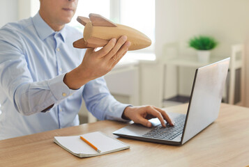 Close up shot of a businessman in office working on laptop. Holding rocket symbolizing startup,...