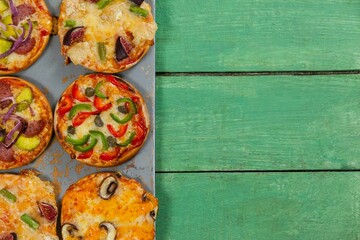 Pizzas arranged on green wooden table
