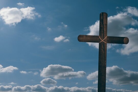 Wooden cross is standing against open sky with natural rope and cumulus clouds in flat design