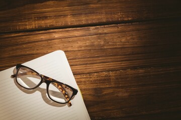 Reading glasses on book over wooden table