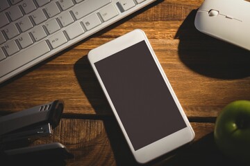 Flat design is showing white smartphone resting on desk with keyboard, mouse, power banks and apple