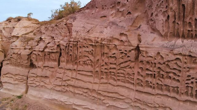 Aerial footage showcasing intricate patterns and textures of naturally eroded sandstone cliffs, revealing unique geological formations and striking rock sculptures shaped by wind and water over time.